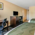 Two Queen Bed Ends across from Desk, Chair, Dresser, and TV at Quality Inn & Suites Albany